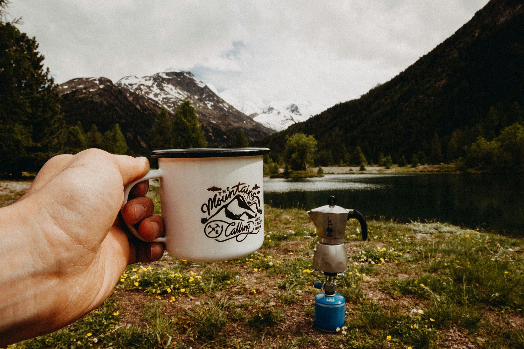 Person holding coffee mug with mountains in background