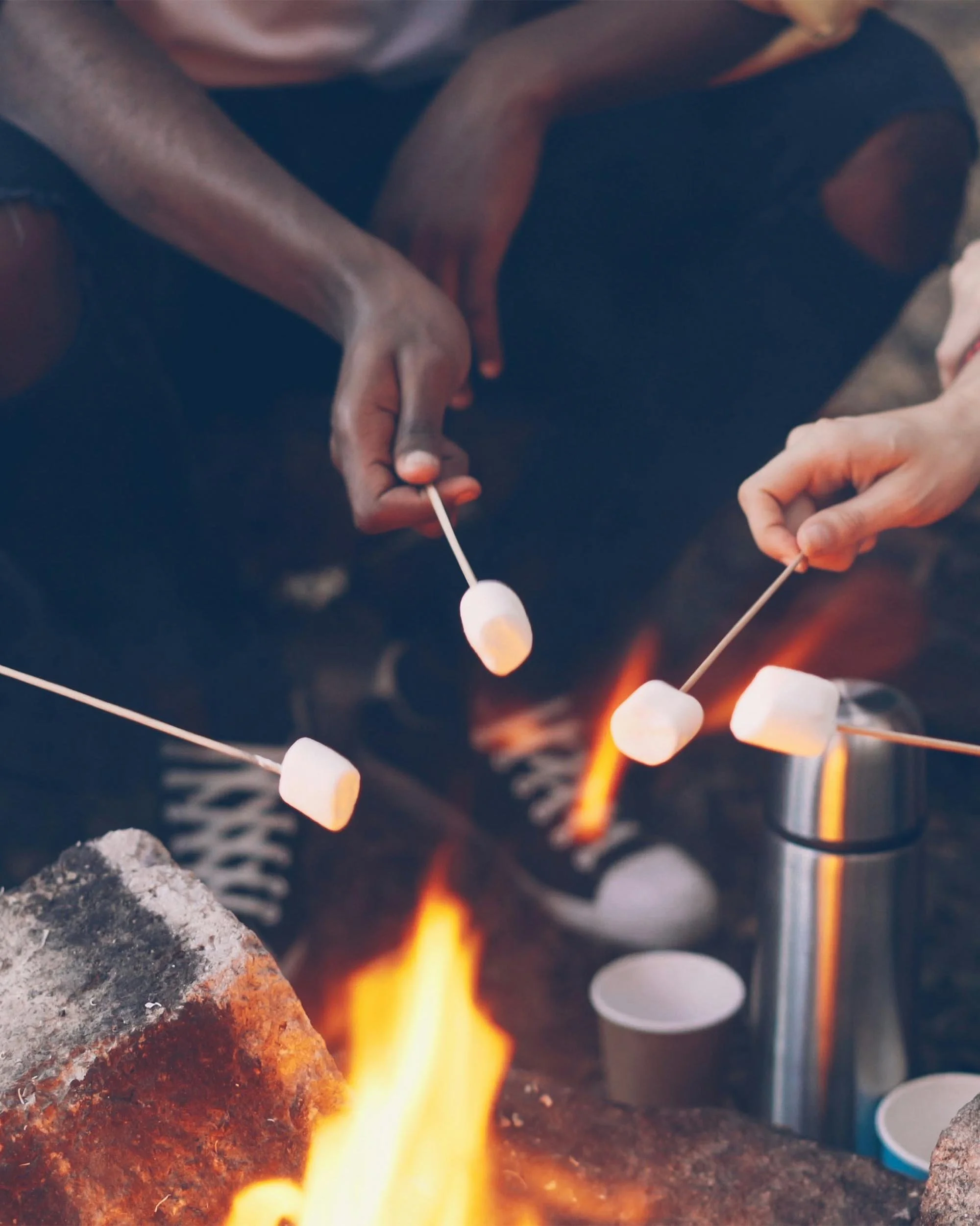 Group of people roasting marshmallows over a fire