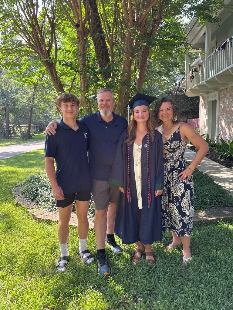 A smiling woman with short black hair in an indoor botanical setting.
