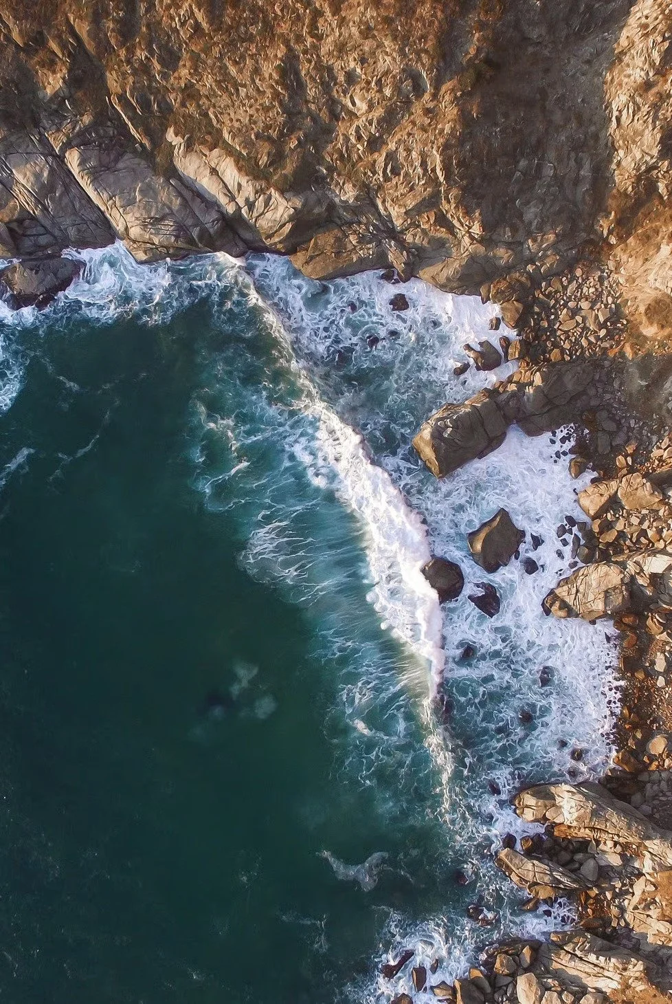 Aerial view of a rocky coastline with ocean waves crashing against the rocks.