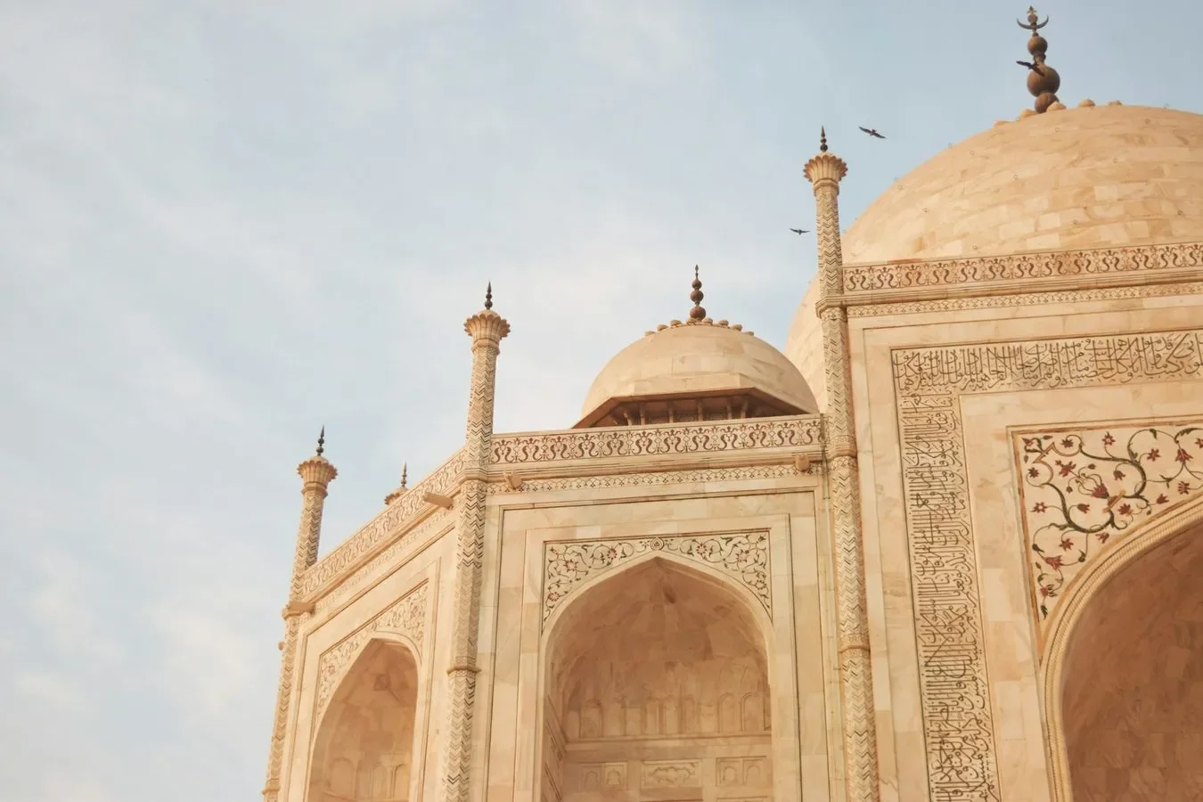 Close-up of the Taj Mahal's intricate marble facade with minarets and domes, featuring detailed carvings and calligraphy.