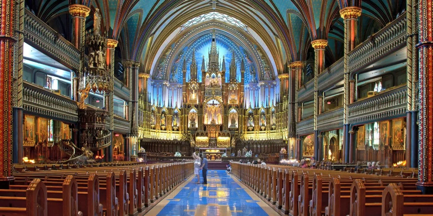 Interior of a grand church with intricate Gothic architecture, stained glass windows, and ornate decorations, including wooden pews and an elaborate altar.