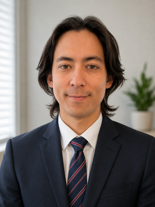 Professional man in a navy suit and striped tie, smiling in an office setting with a potted plant in the background.