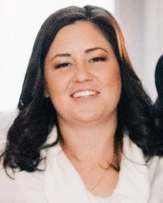 A woman with dark, shoulder-length hair smiling at the camera.