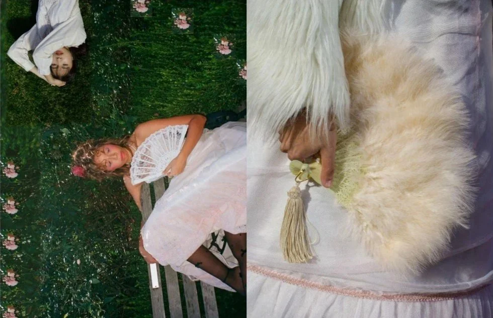A woman dressed in white lying on a bench in a garden with pink flowers, making a peace sign; another woman dressed in white with black tights sitting on the ground, holding a white lace fan, wearing a pink flower crown; close-up of a hand holding a fluffy white fan with a tassel.