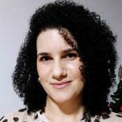 Close-up portrait of a woman with curly black hair, smiling softly at the camera.