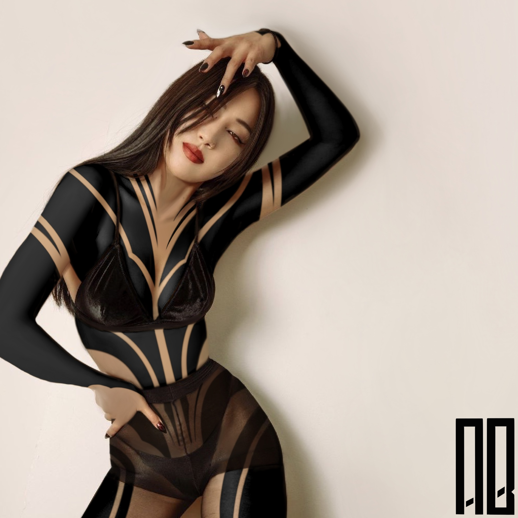 Woman in black and tan patterned bodysuit with long black sleeves, posing against a plain wall, with her hand in her hair and her other hand on her hip.
