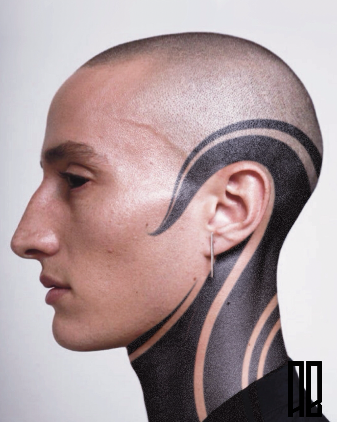 Side profile of person with shaved head and facial tattoos, wearing a small hoop earring and a stylized black and pink tattoo design on the neck.