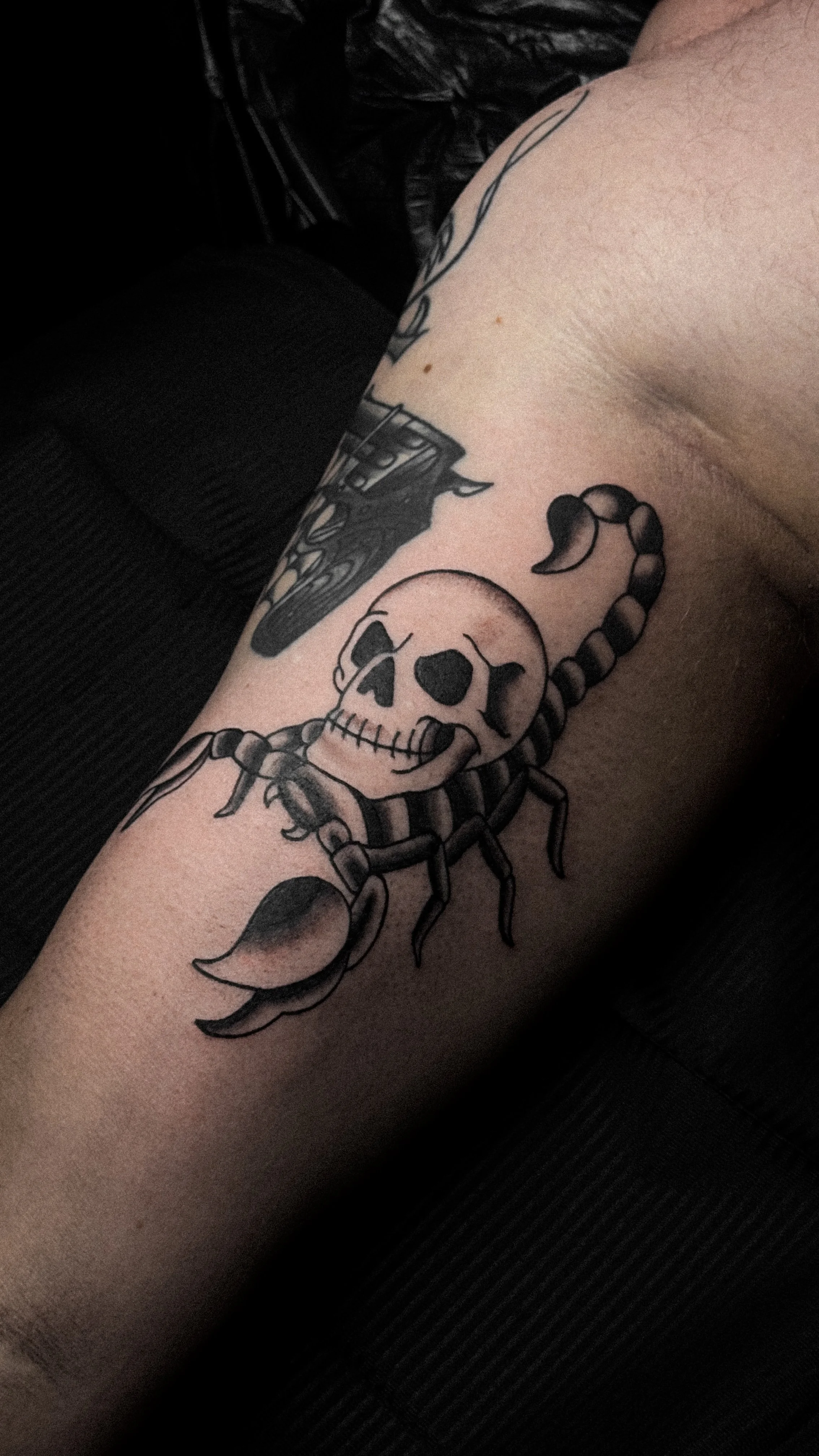 Tattoo of a scorpion with a skull body on a person's arm.
