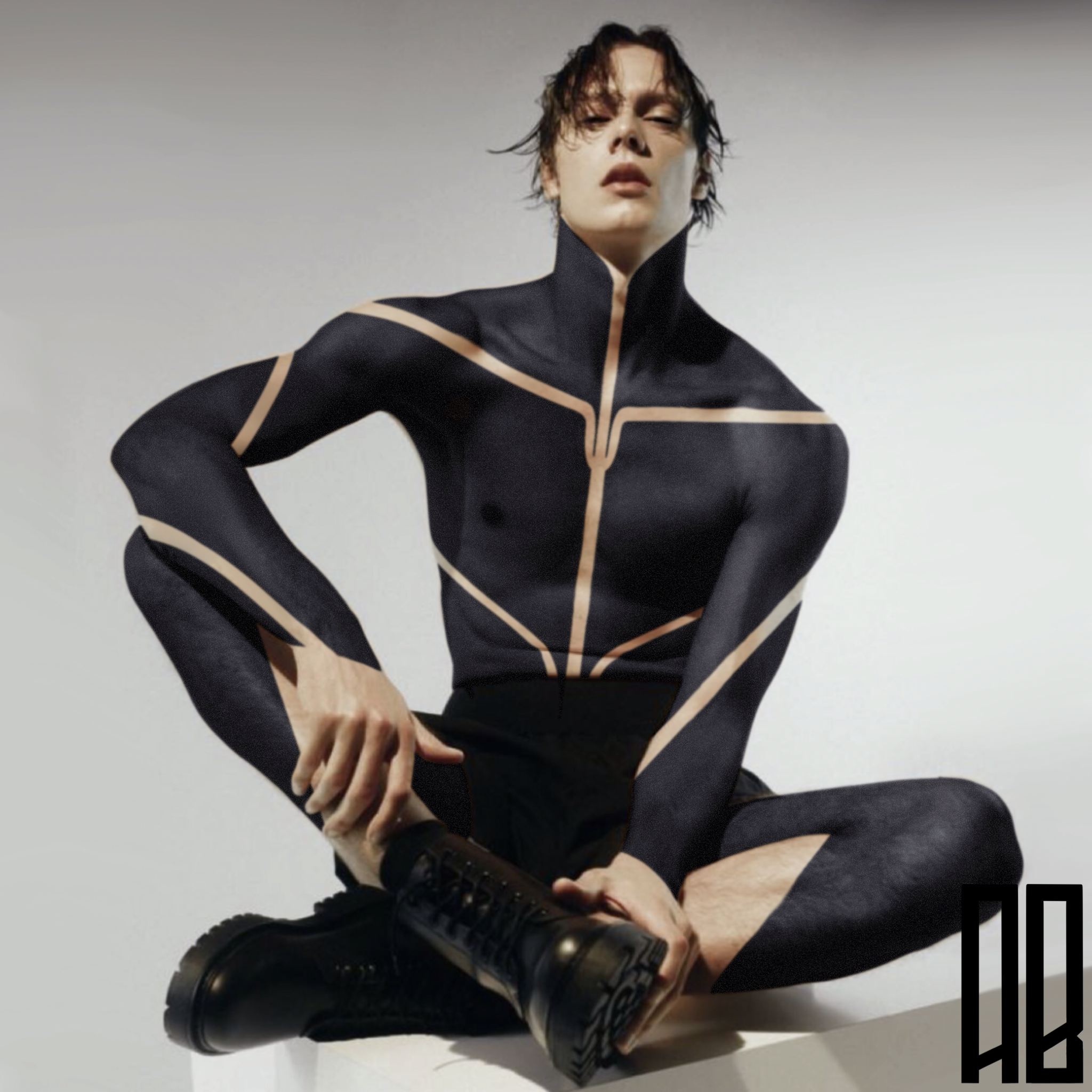 A person with short, messy dark hair and pale skin, wearing a black bodysuit with beige piping, sitting cross-legged on the floor, with their hands on their knee and foot, against a plain white background.