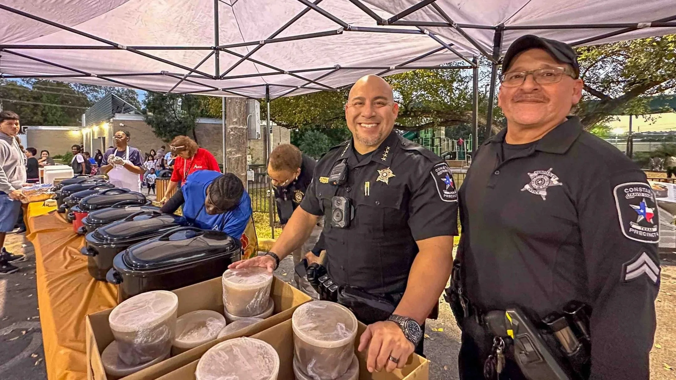 Smile of Constable Gabe Padilla at a community event with food containers on a table.
