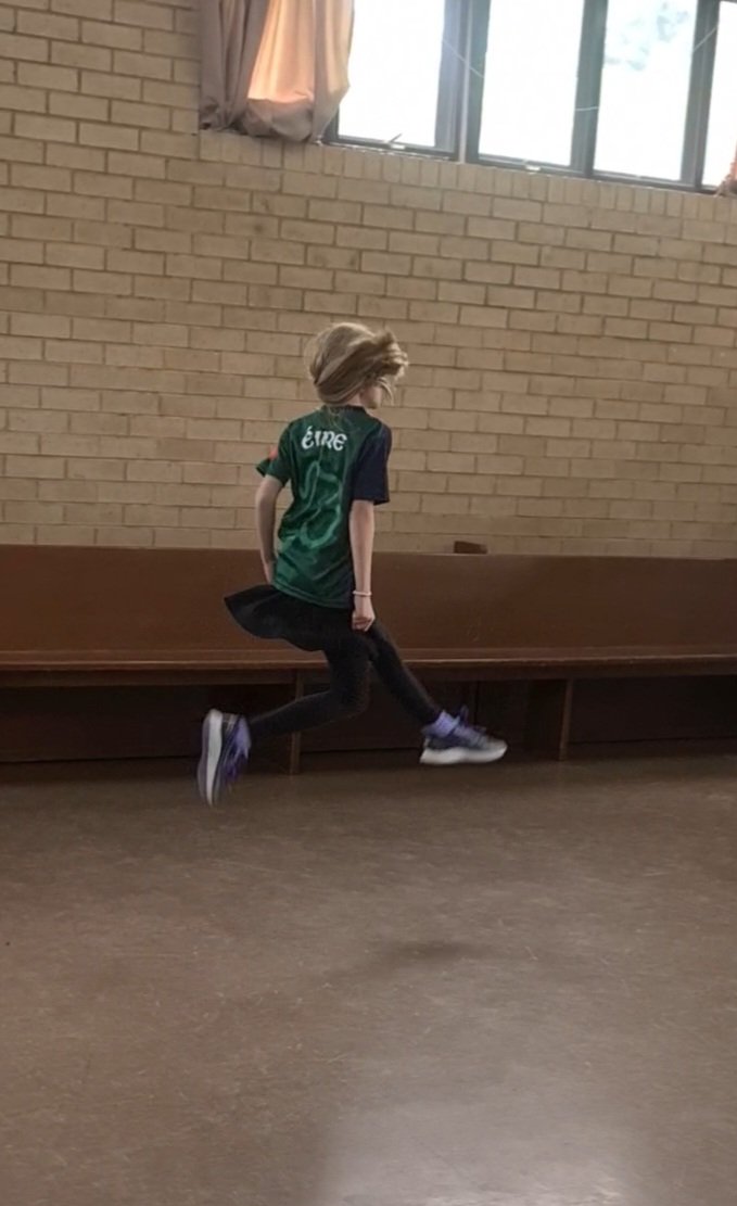 Irish dance student performing an action shot, showcasing technique, form and movement.