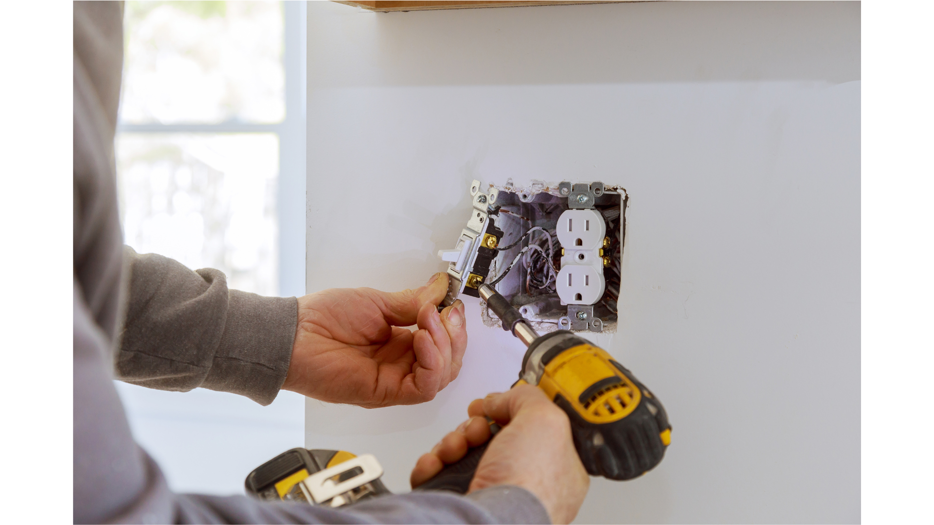 Person installing or repairing electrical outlets in a wall using a cordless screwdriver.