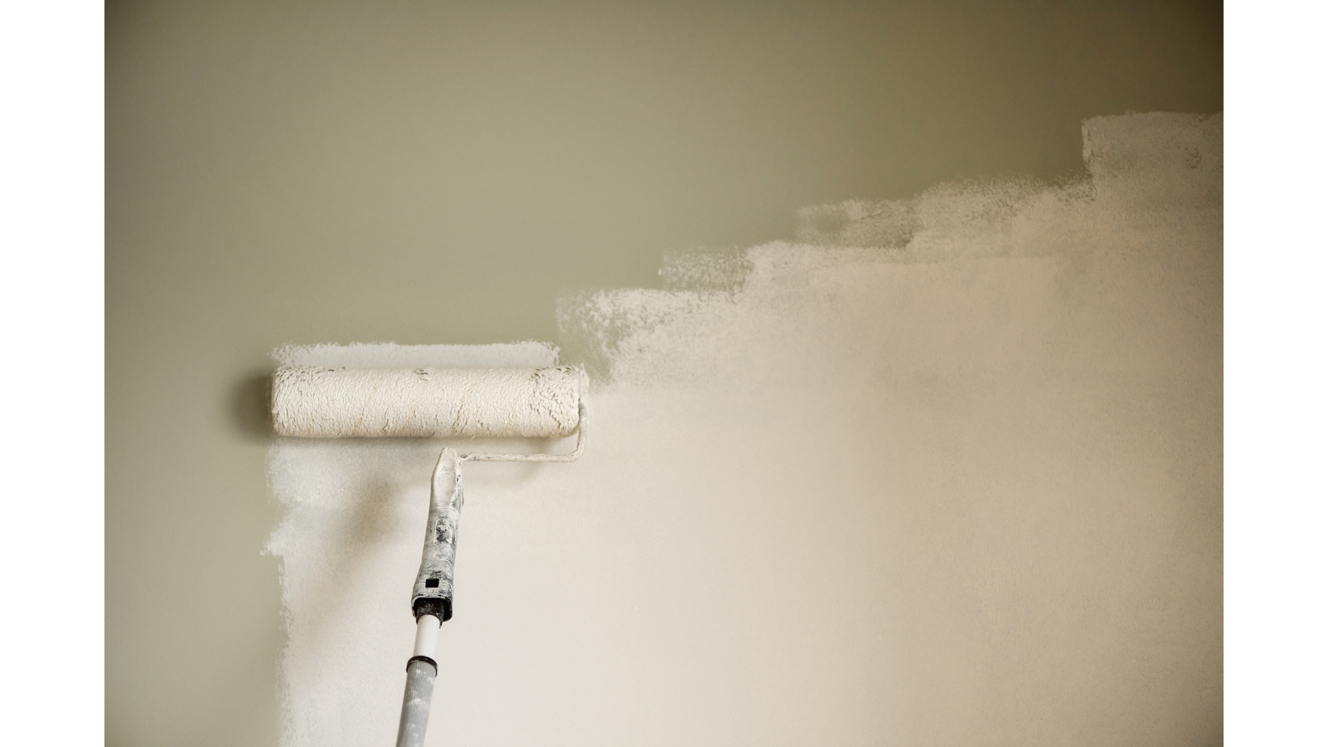A paint roller applying beige paint to a wall.