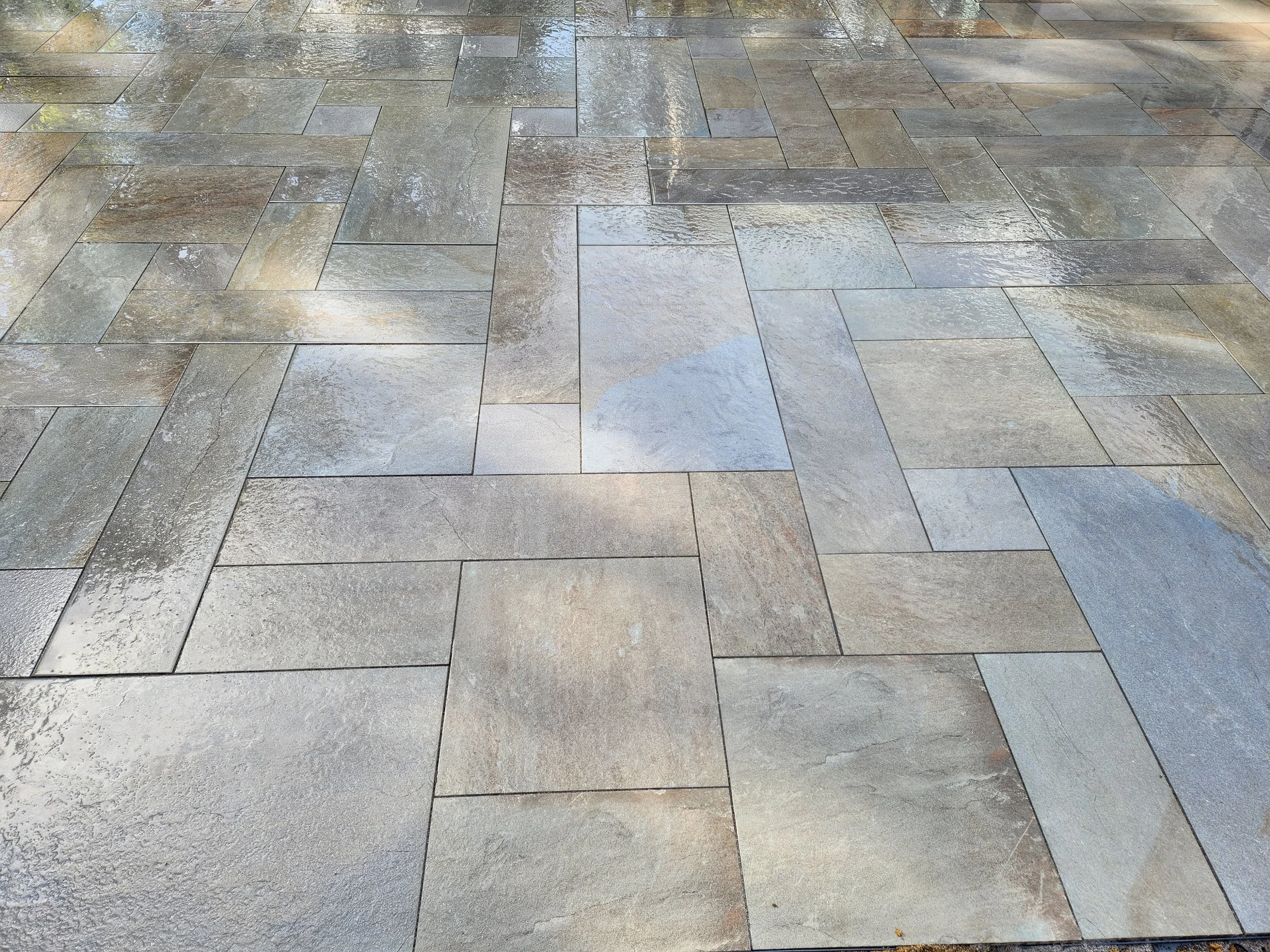 Wet, multicolored stone tile pavement with reflective surface.