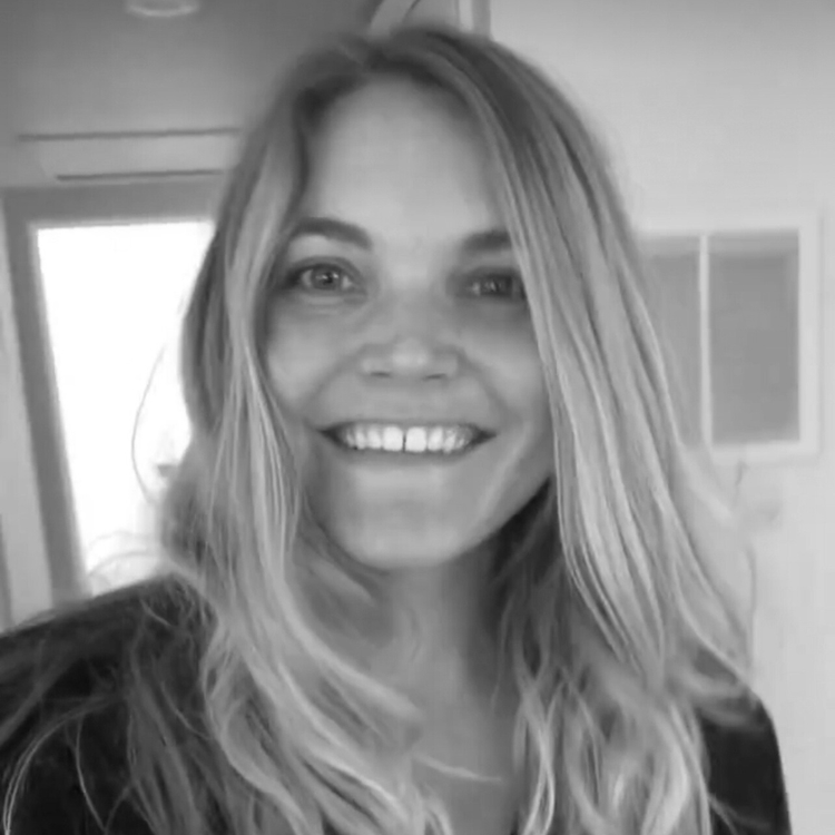 A woman with long, wavy hair smiling at the camera in a black-and-white photo.
