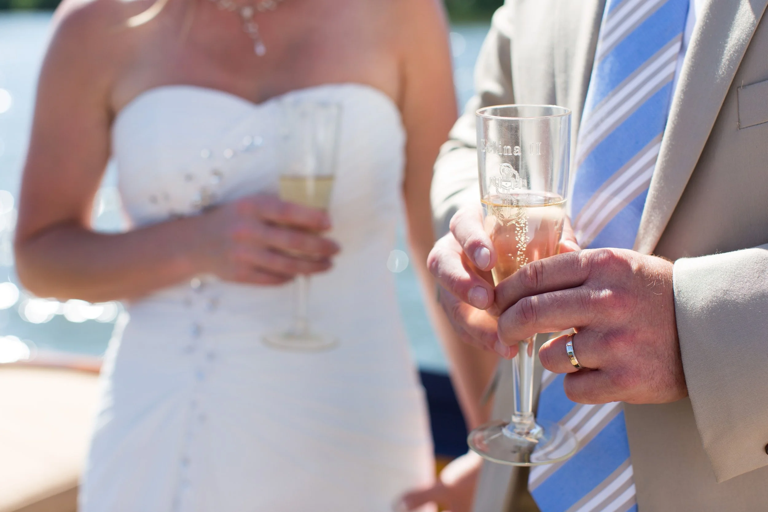 Newlyweds holding their custom-engraved champagne flutes provided by the crew of Selina II as a part of the Nautical Wedding Package.