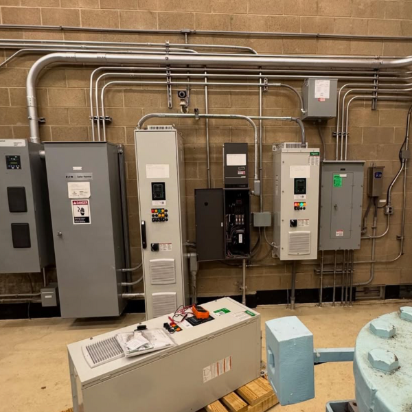 Electrical control panels and wiring on a brick wall in an industrial setting.