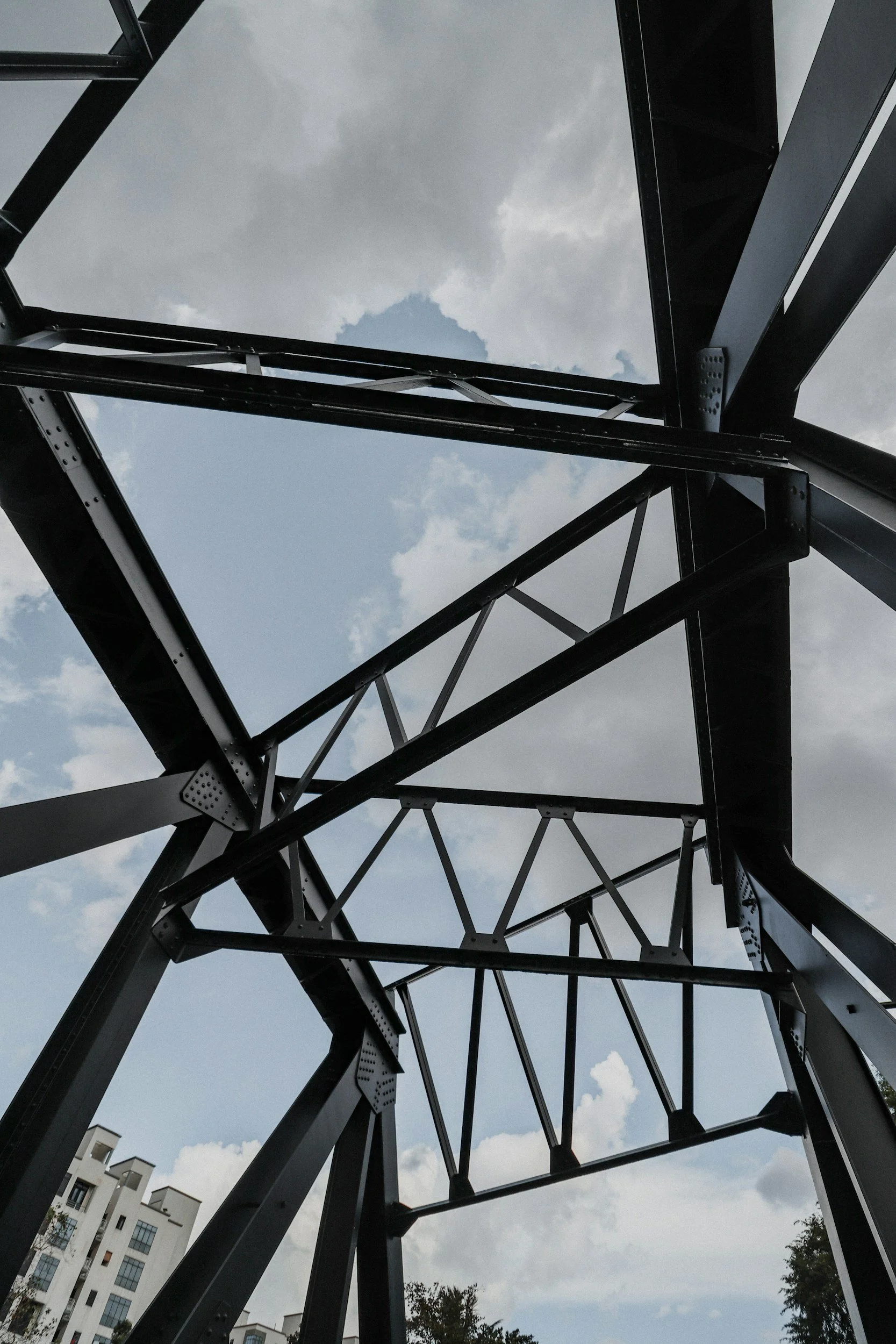 Looking up at a metal structure against a cloudy sky with residential buildings in the background.