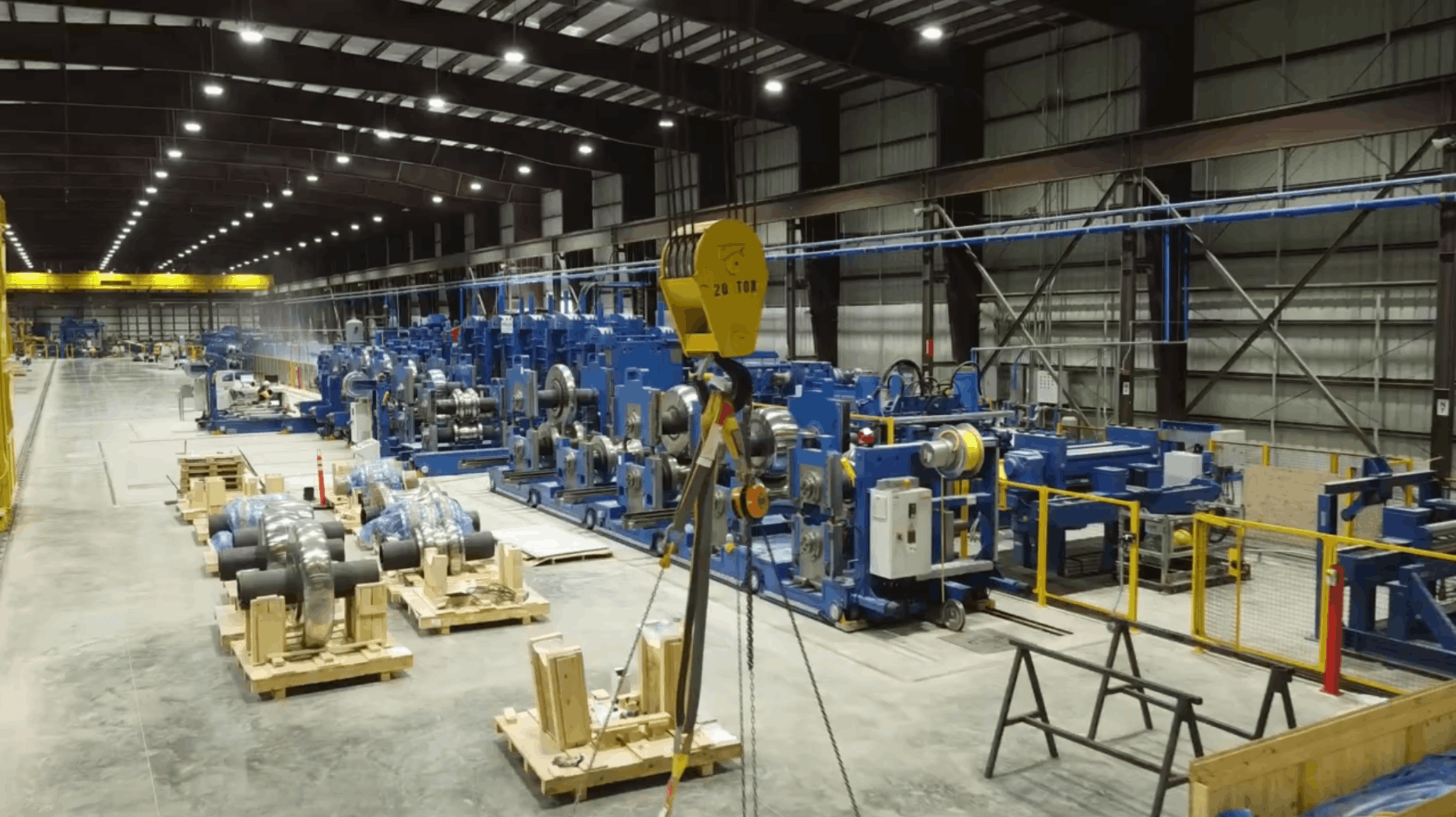 Wide view of factory floor with large-scale industrial equipment and materials staged for processing.