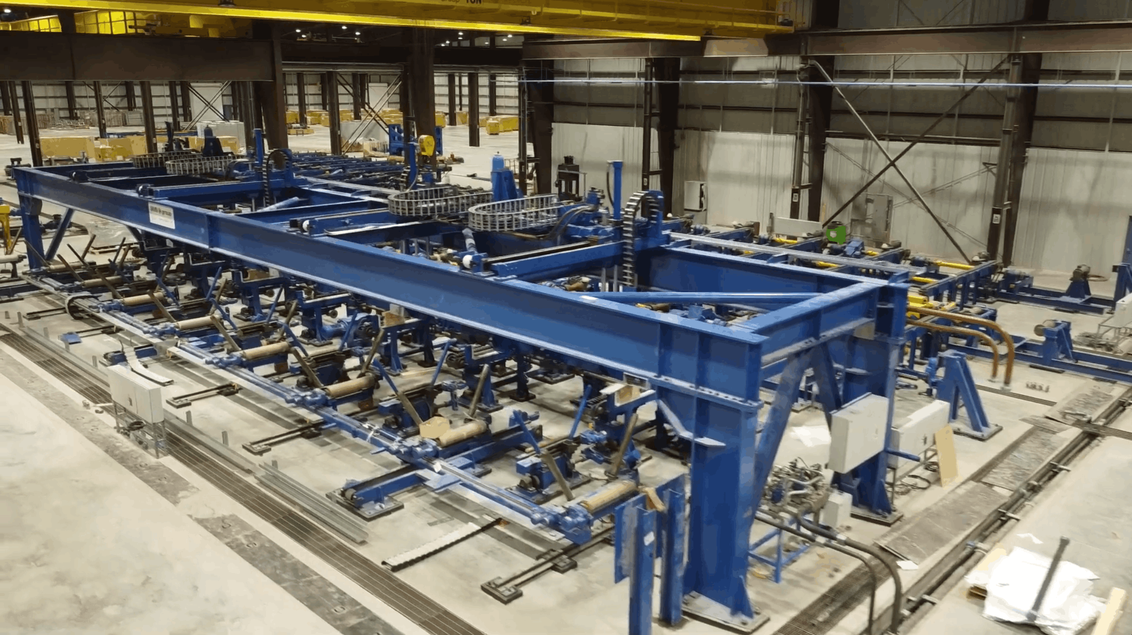 Industrial production line with heavy machinery and workers inside factory.