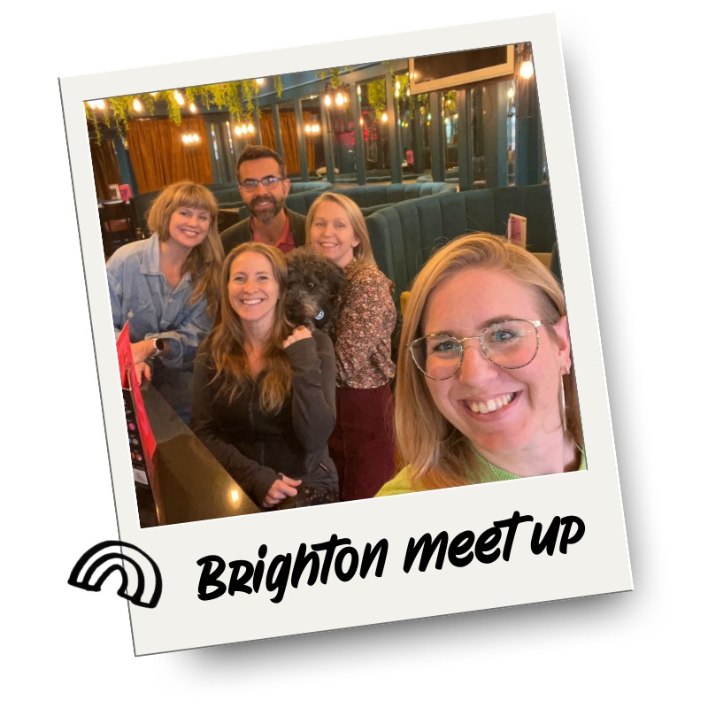 Group of five people and a dog smiling for a photo at a Brighton meetup in a restaurant or cafe with string lights and a cozy interior.