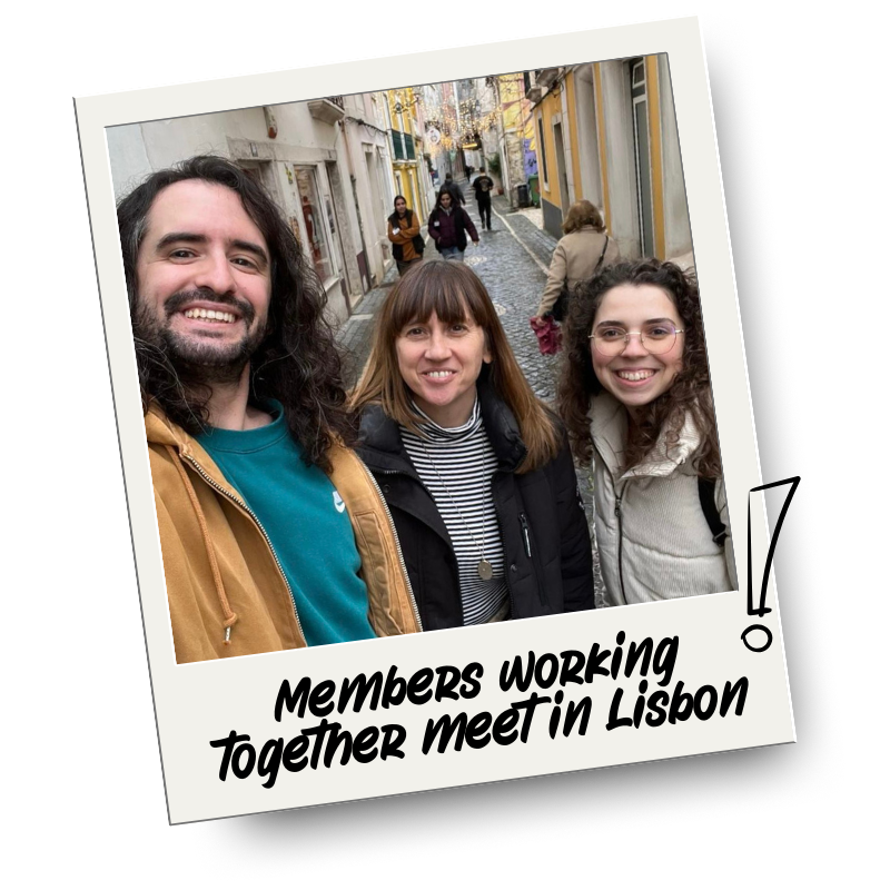 Three people standing on a cobblestone street in Lisbon, Portugal, smiling at the camera. The street is lined with colorful buildings and other pedestrians pass by.