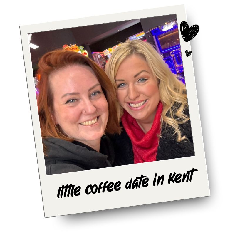 Two smiling women taking a selfie together in a lively, brightly lit arcade or amusement area. The photo is framed like a Polaroid with the caption 'little coffee date in kent' at the bottom.