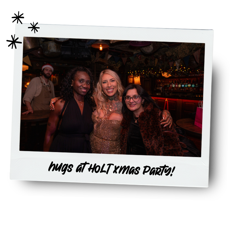 Three women posing and smiling at a Christmas party, with a bartender and festive decorations in the background, and a caption reading "hugs at HOLT xmas party!"