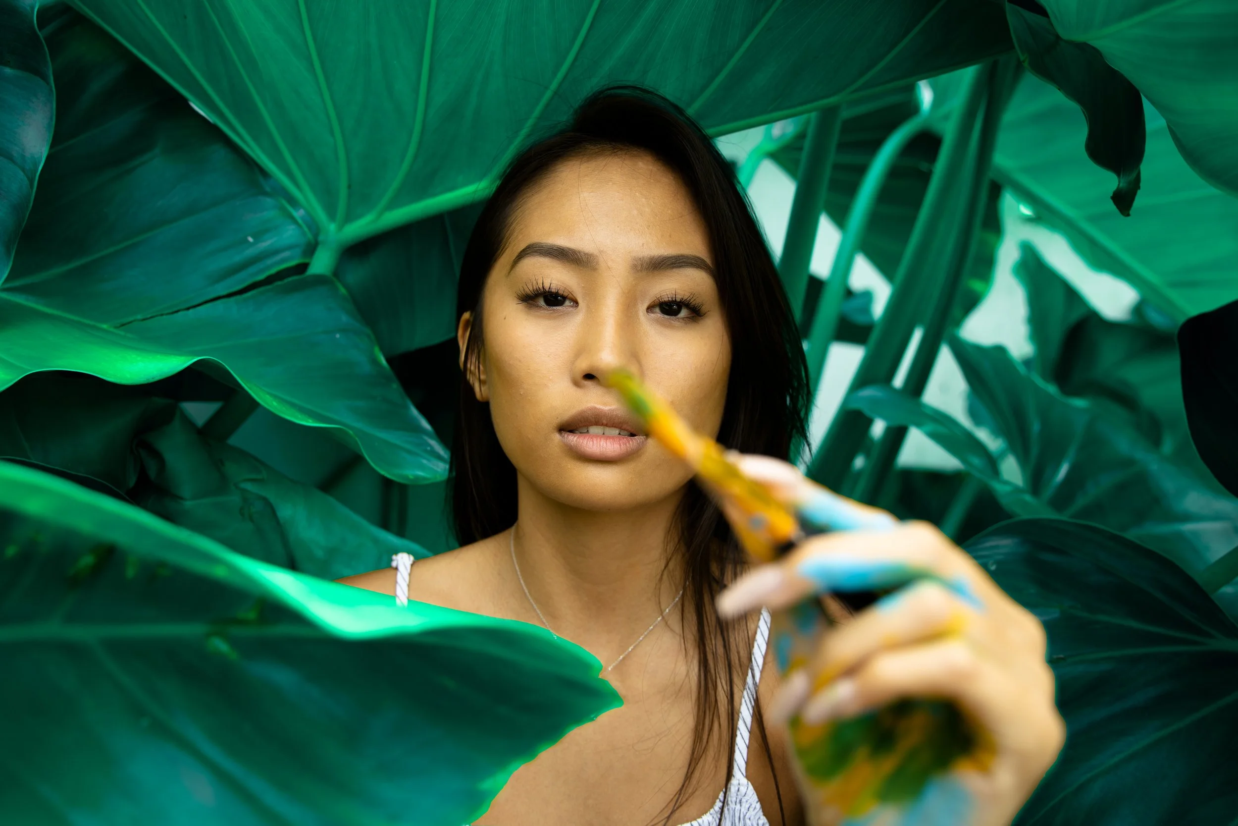 Creative outdoor portrait of a woman surrounded by tropical leaves, photographed in natural light in Oahu