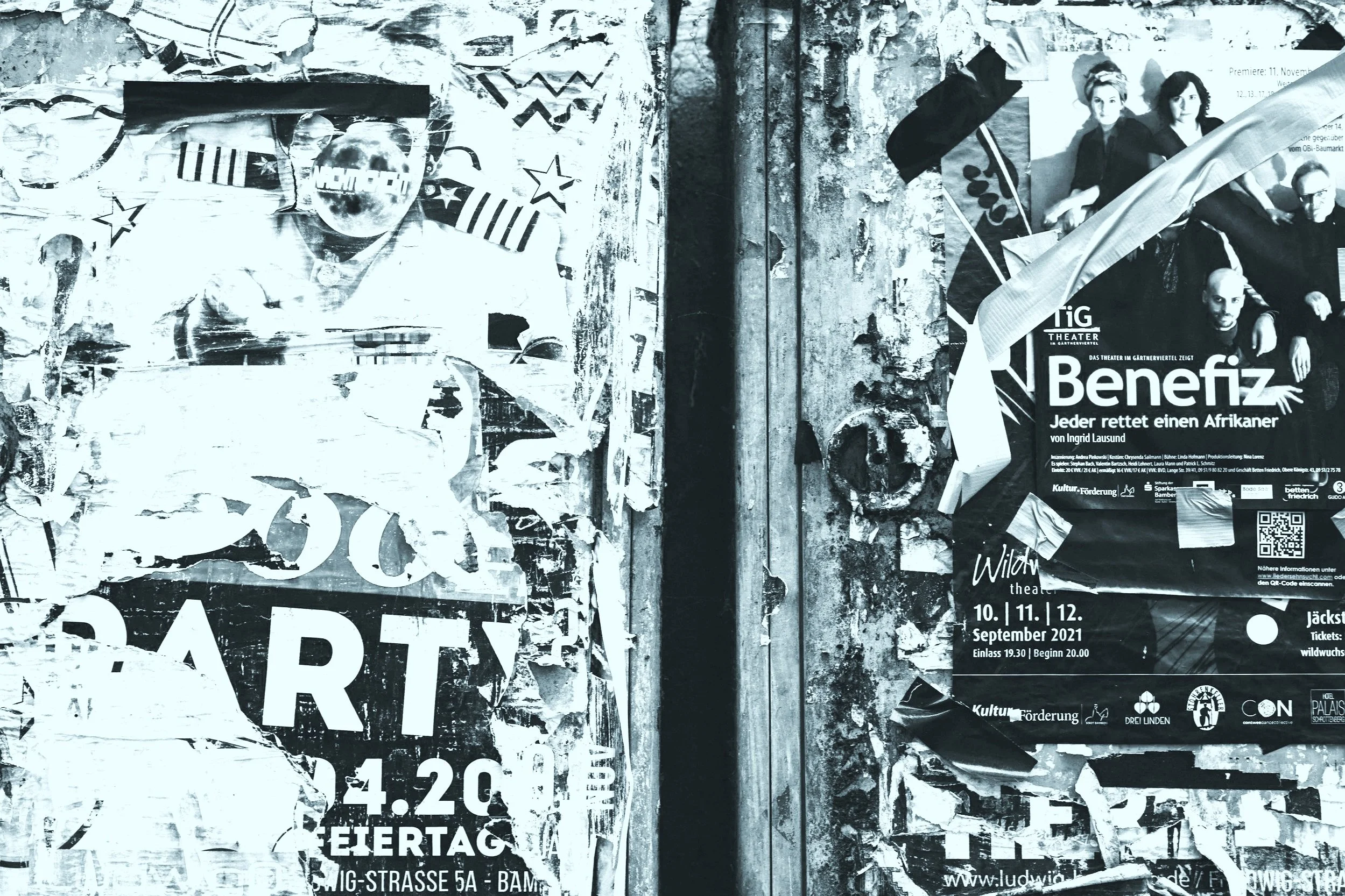 Close-up of weathered and torn posters on a wall, displaying event advertisements, one showing a person in a graduation cap and gown, other showing a group of people with one man with a shaved head, and various texts and logos.