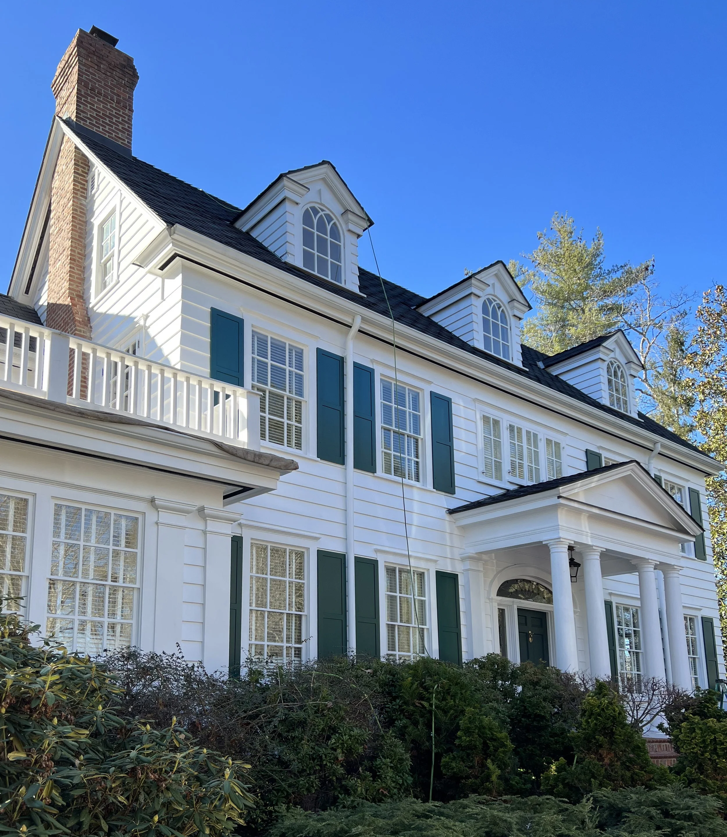 Large colonial house, white with shutters and dormers.