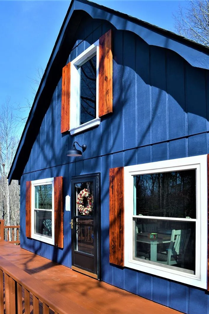 This Franklin AirBnB cabin was refurbished from top to bottom. Painted siding with Benjamin Moore color, Hale Navy, we added wood shutters and painted the decks — it was a washed-out 1970s peach.