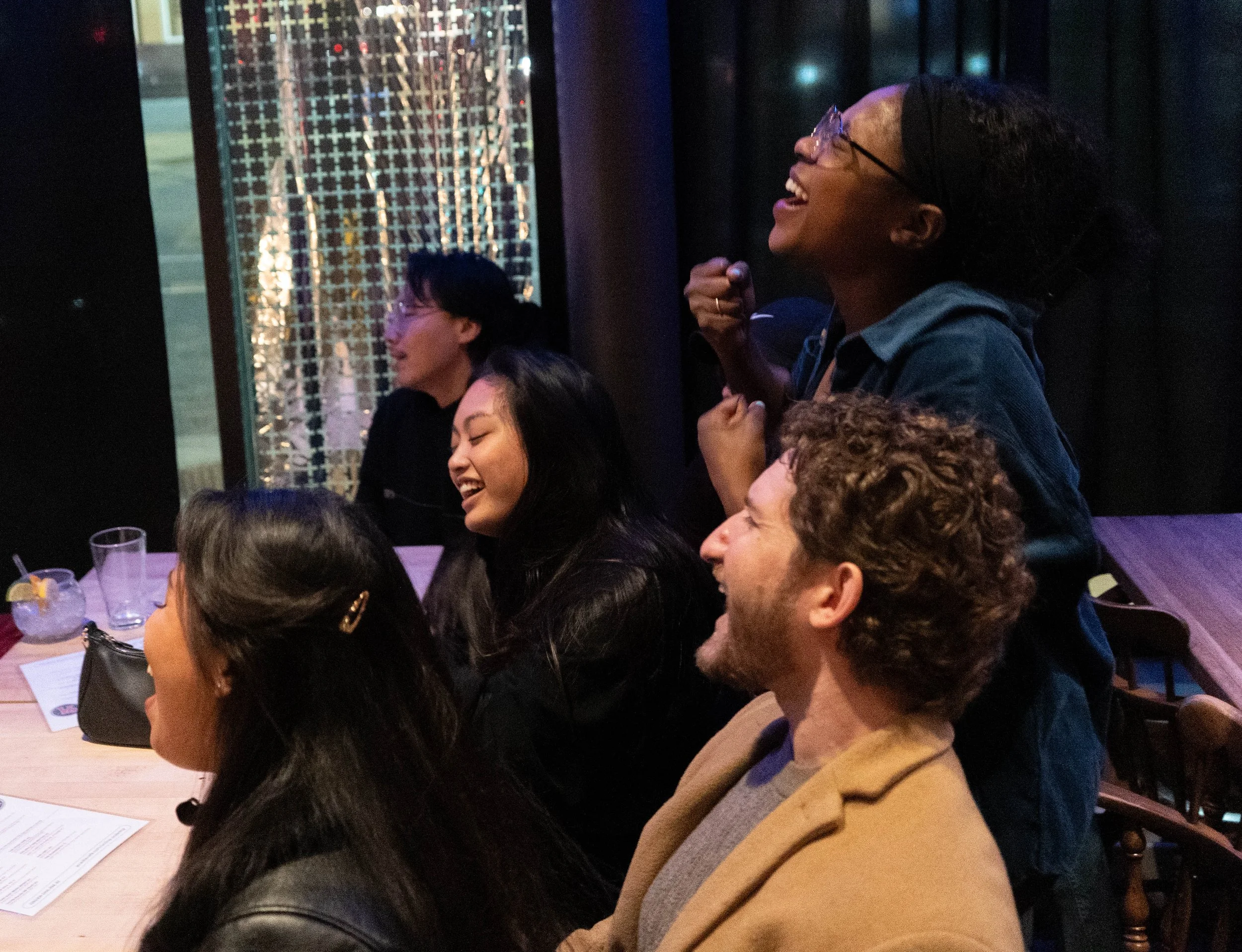 Friends of the band Romilyn Sotto, left, Kou Yang, Brendan Bonnell and Nhina Nyirenda sing along to False Start during their performance at Acadia bar and grill in Minneapolis, Minn., on Nov. 24, 2025. Nyirenda was in and out of her seat during the b