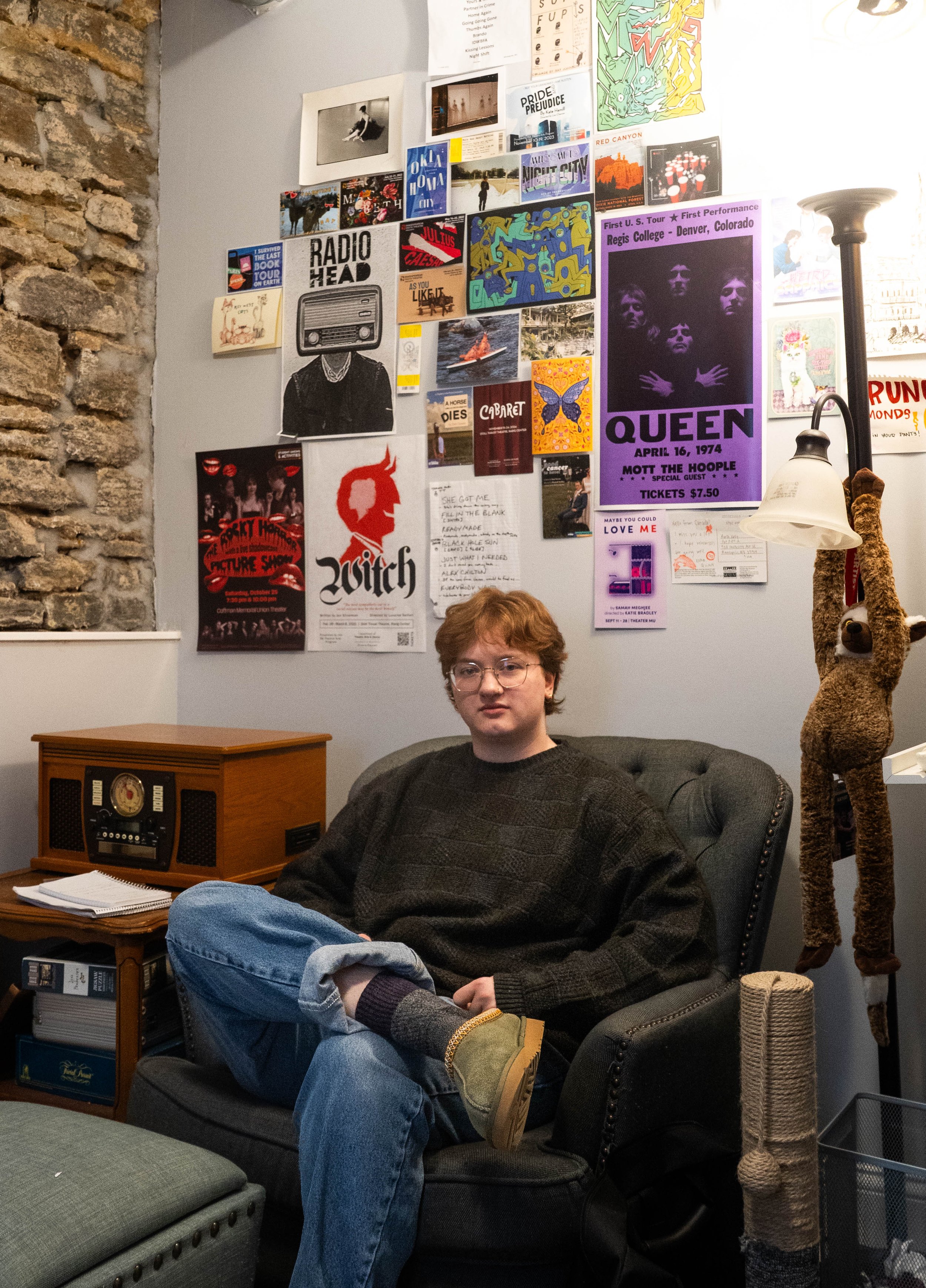 Marsh Kelly sits below an array of posters on the wall of his bedroom in his home in Minneapolis, Minn. on Feb. 18, 2026. Kelly's wall includes the posters of some of the productions he's participated in.