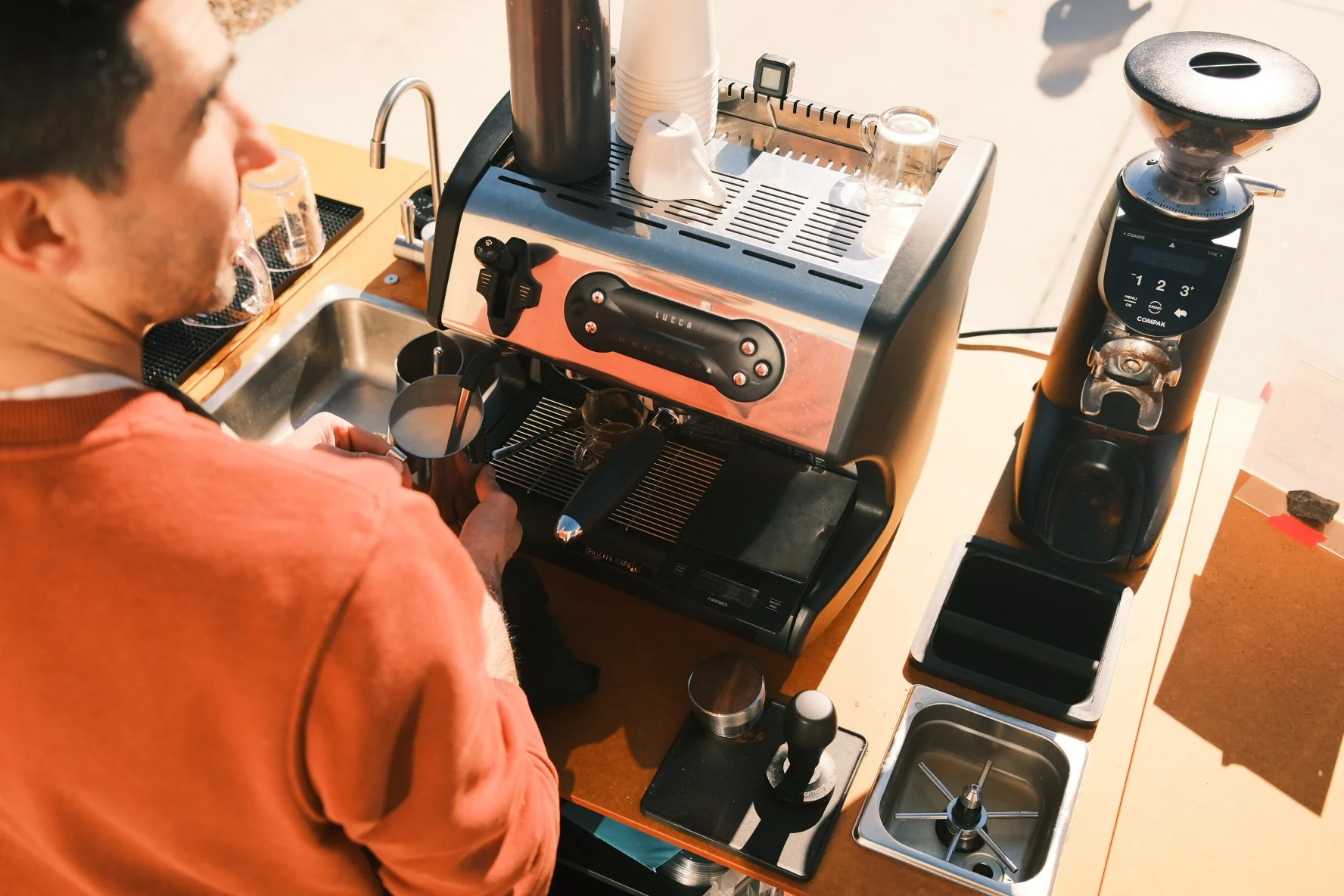 Barista steaming milk interacting with customers