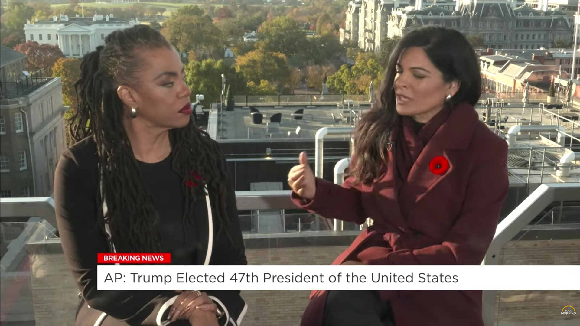 Two women sitting on a rooftop, engaged in conversation with the U.S. Capitol building in the background. One woman has long dark hair, and the other has long dreadlocks. Both are dressed in dark clothing; the woman with long dark hair is wearing a dark jacket with a poppy pin, and the woman with dreadlocks is wearing a dark top with white accents. A news banner at the bottom reads: "BREAKING NEWS AP: Trump Elected 47th President of the United States."