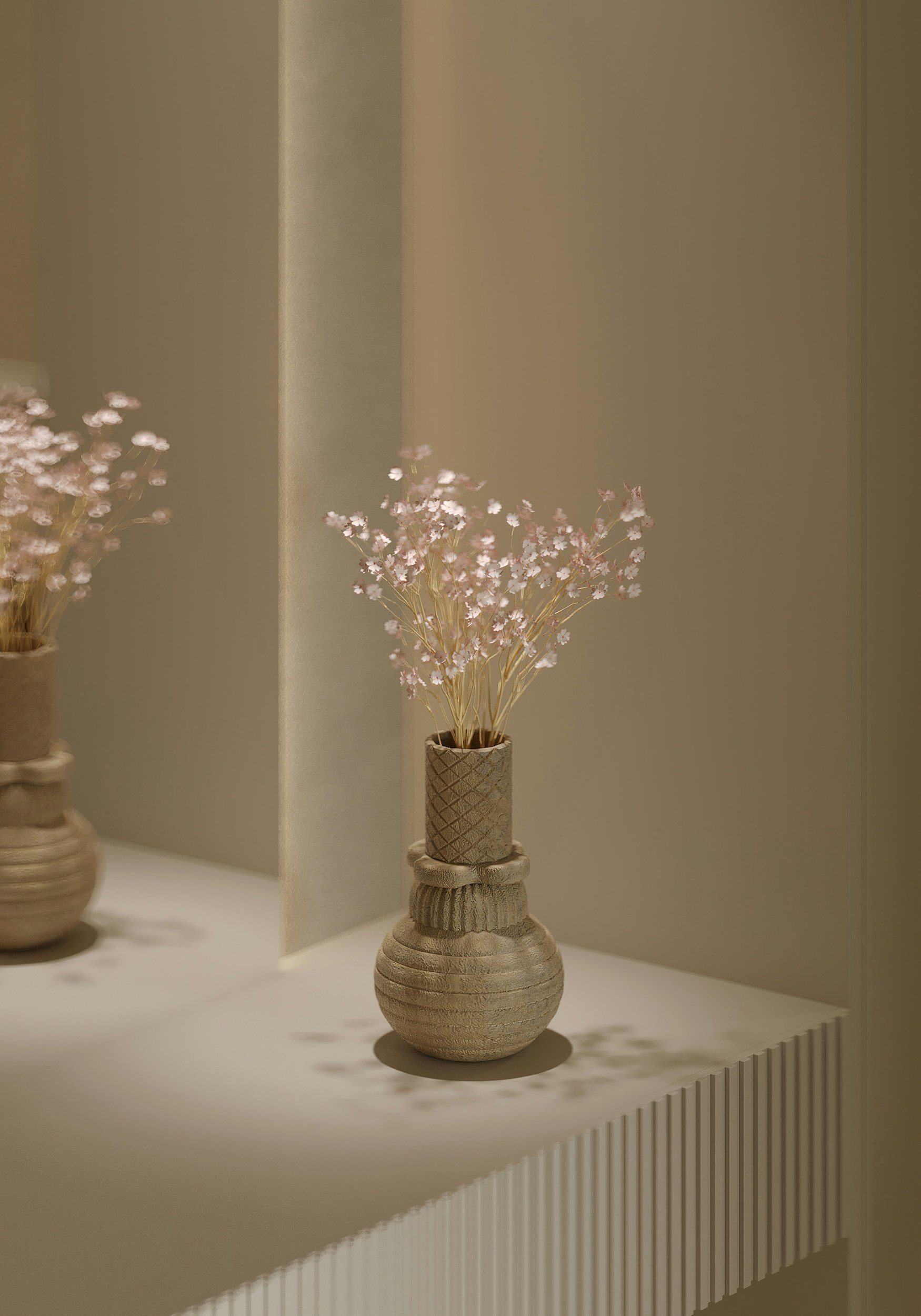 A beige textured vase with a narrow neck and rounded body holding small white and pink flowers, placed on a white surface with a subtle shadow, against a neutral background.