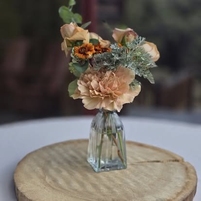 A single bud vase of farm-grown peach and orange dahlias — the kind of detail that makes a farm table feel like it grew there. Cherokee Bloom, Salida, Colorado