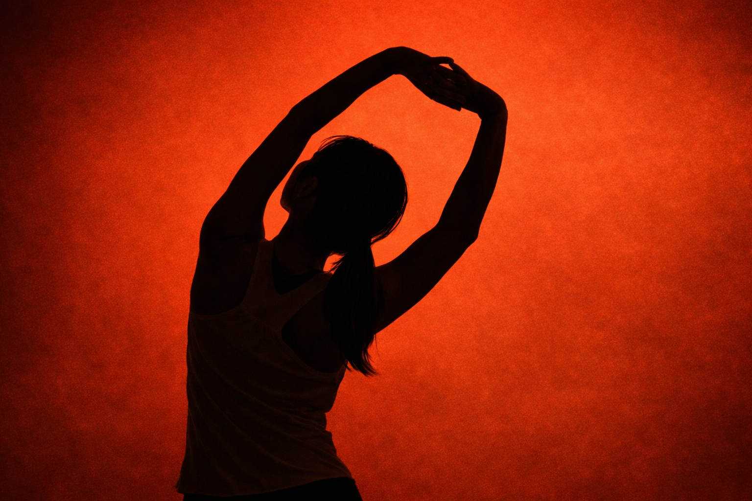Silhouette of a woman stretching with her arms raised, against a red-orange background.