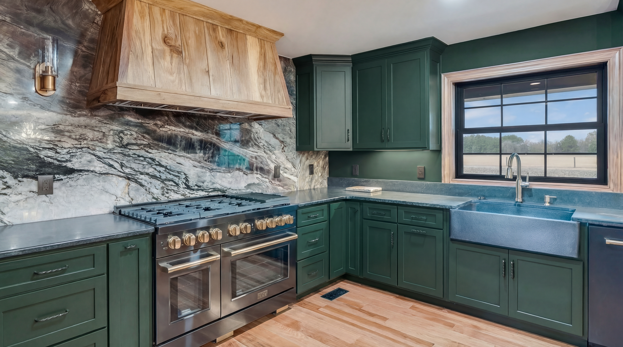 Modern kitchen with green cabinets, a gray marble backsplash, a large window above a farmhouse sink, and a stove with brass knobs.