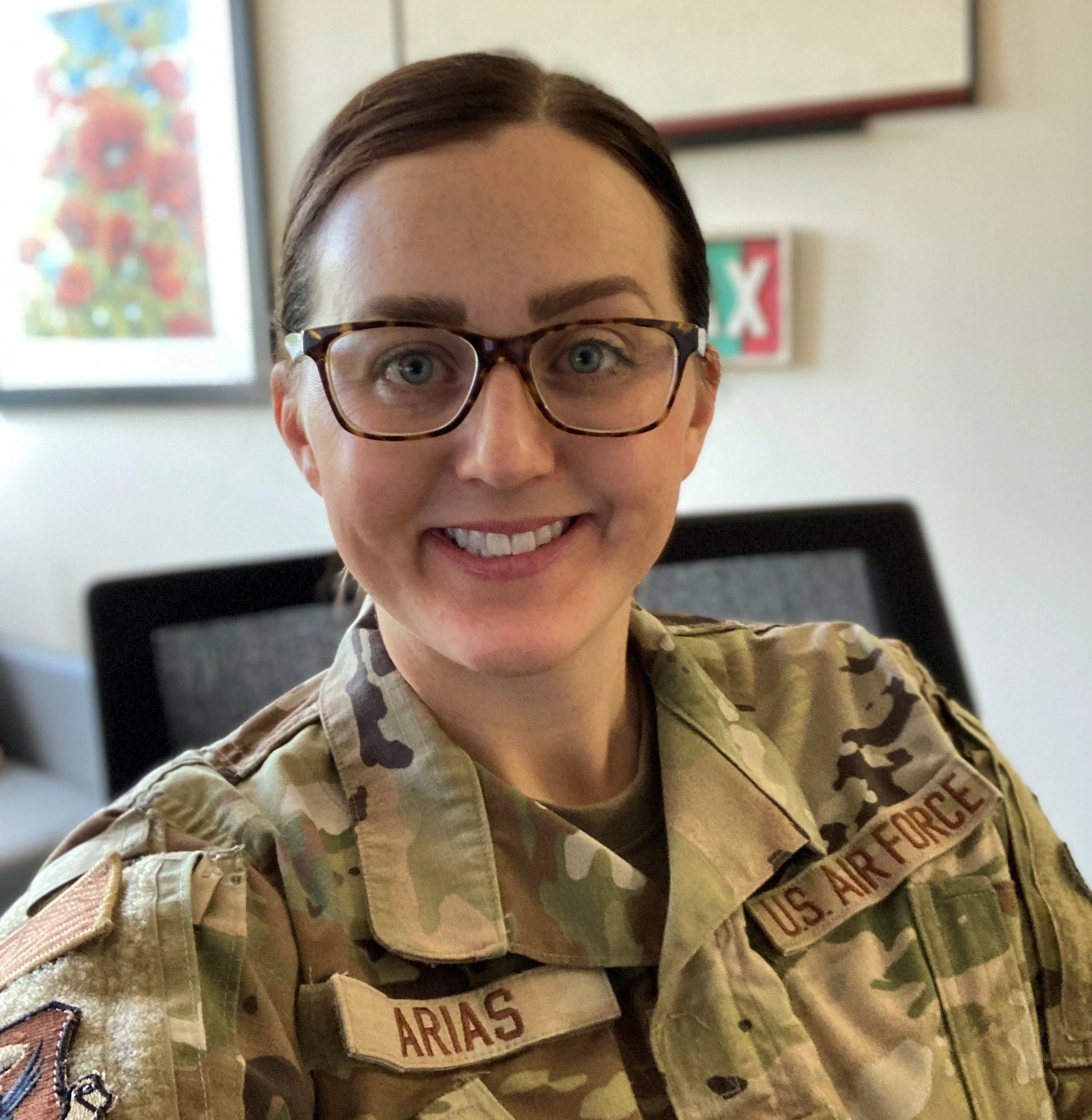 A woman in U.S. Air Force uniform smiling for a selfie in an indoor setting.