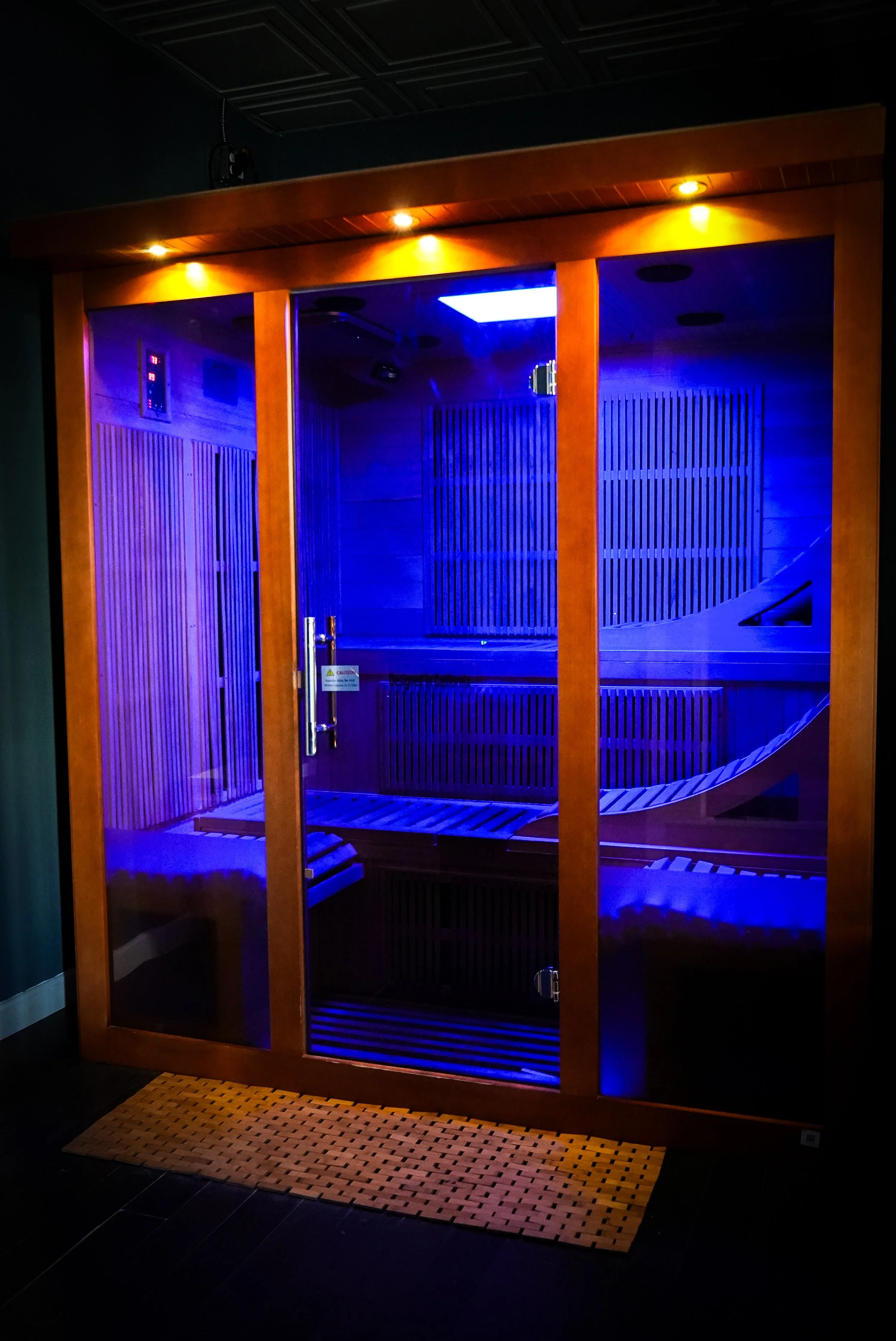 A wooden slide inside a glass enclosure illuminated by blue and warm lighting.