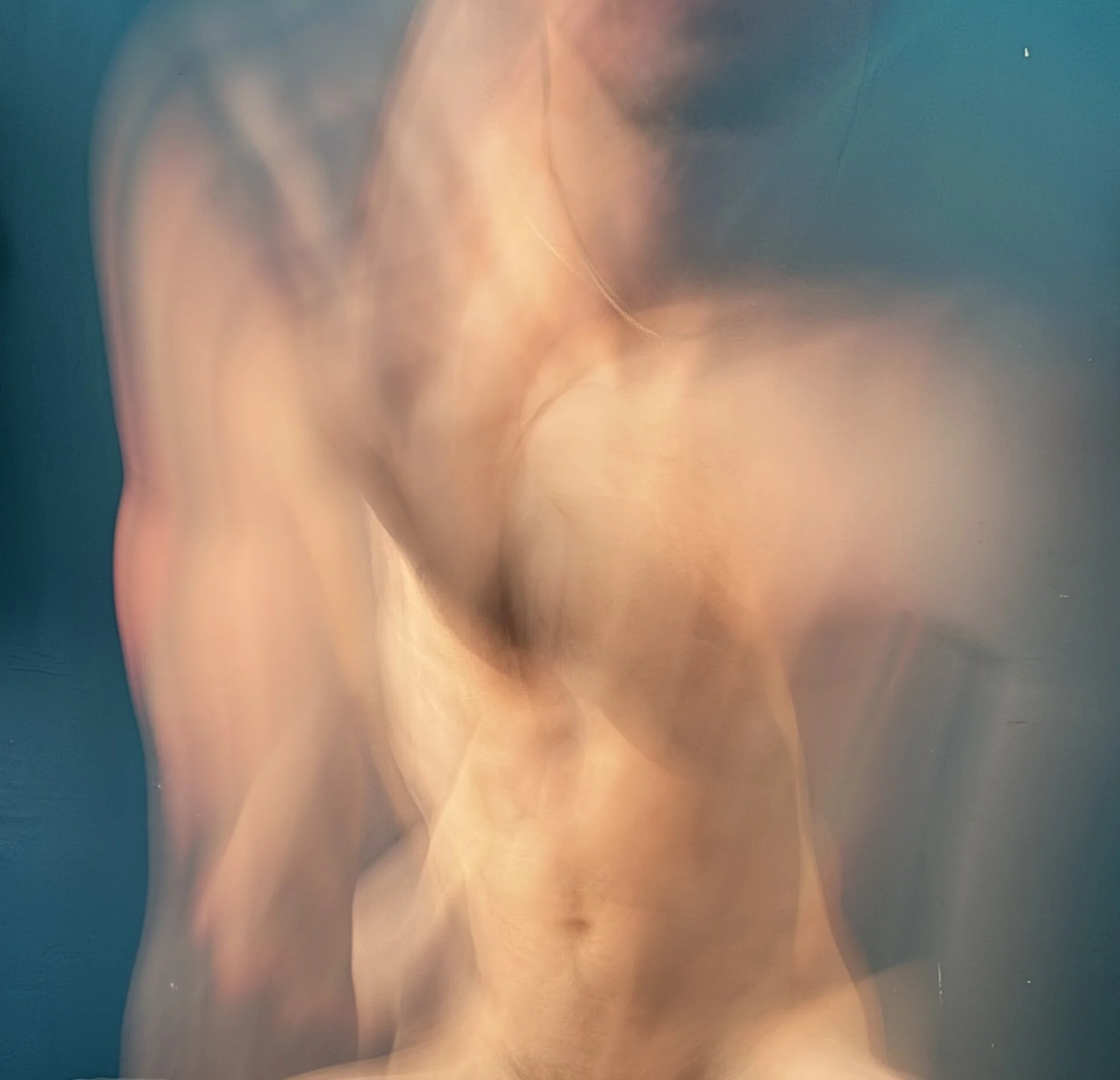 Abstract, blurred image of a person's upper body and face, with warm skin tones and soft lighting.