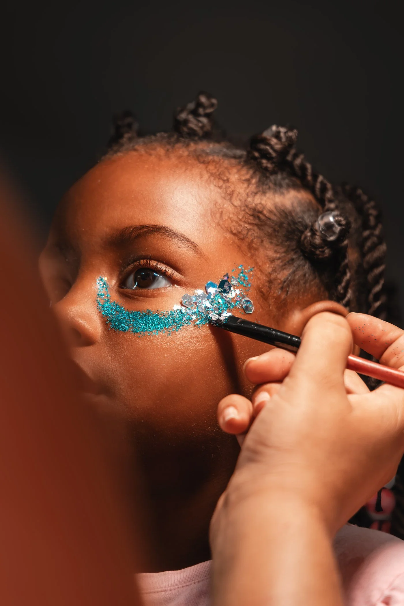 Application au pinceau d’un maquillage pailleté bleu et argenté