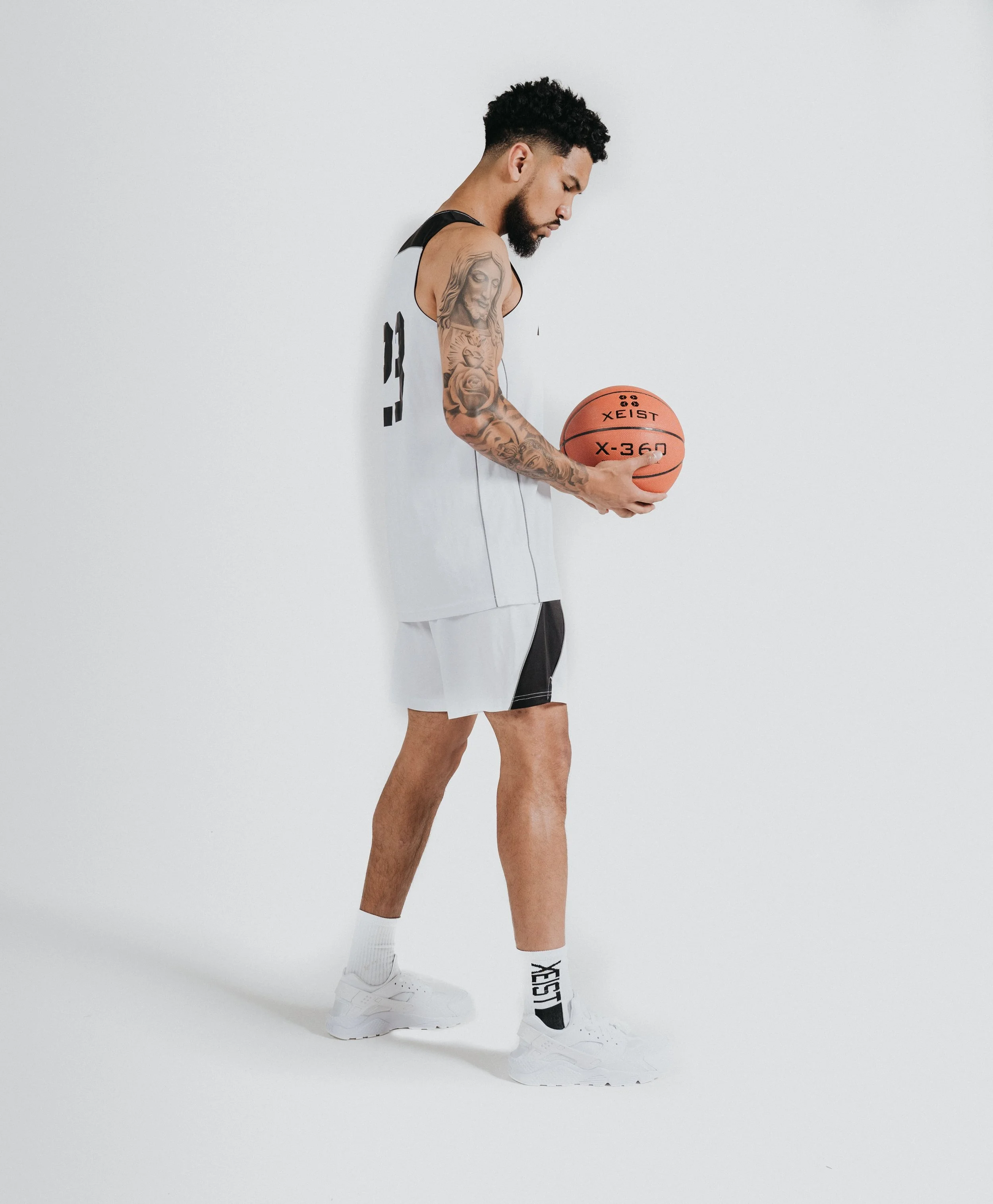 A young man in a sports uniform holding a basketball, standing against a plain white background.