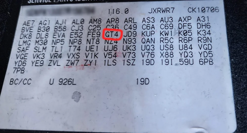 Close-up photo of a parking permit or parking sticker with alphanumeric codes and a red rectangle highlighting the code "GT4".