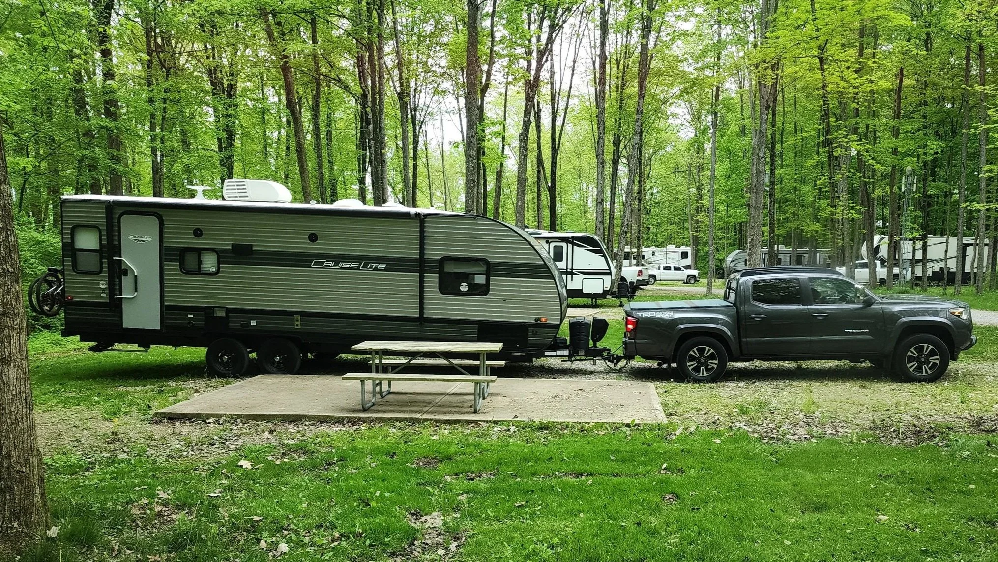 An overloaded Toyota Tundra backs into a camping spot with a very long and heavy  Cruise Lite travel trailer.