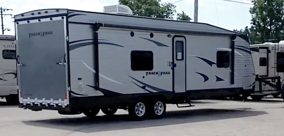A Track & Trail Toy Hauler is towed off by a tractor to be sent back to the factory because of a water leak.