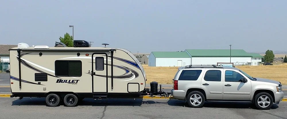 A tan 2007 Chevy Tahoe hitched up to a Keystone Bullet Crossfire travel trailer.